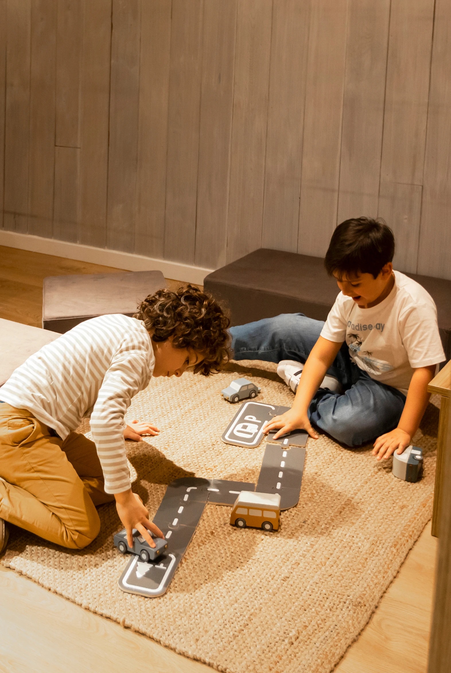 Imagen de dos niños jugando en el suelo con unos cochecitos de juguete.