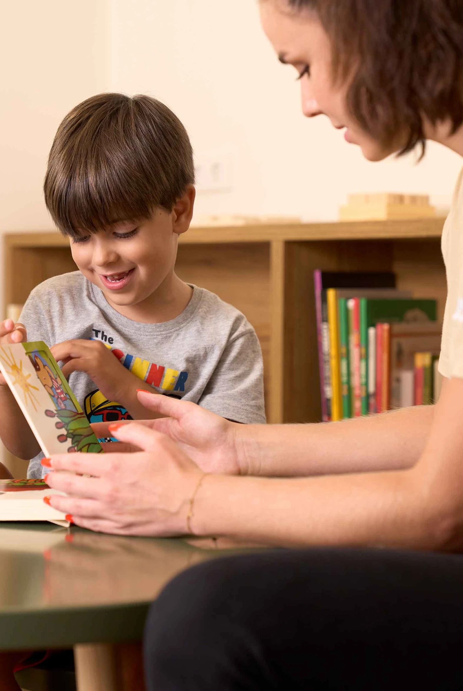 Imagen un niño aprendiendo en una mesa con su profesora.
